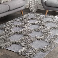 a living room with two gray couches and a rug on the floor in front of it