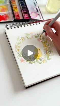 a person is drawing with watercolors on paper