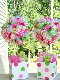 two wreaths with bows hanging from the side of each other in front of trees