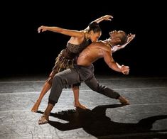 two dancers performing on stage in the dark