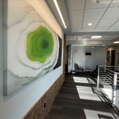 a large painting hanging on the side of a wall next to a stair case in an office building