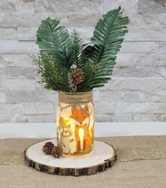 a glass jar filled with plants and pine cones