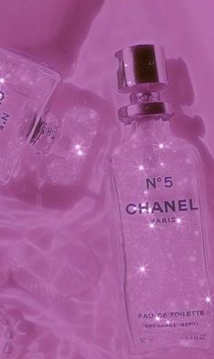 chanel no 5 perfume bottle and ice cubes on pink background with sparkling lights