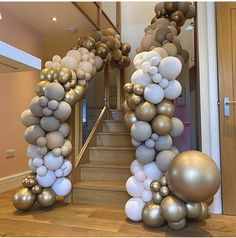 a bunch of balloons that are in the shape of an arch on a staircase with some stairs leading up to it