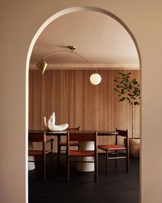 an arch in the wall leads to a dining room with wood paneling and chairs