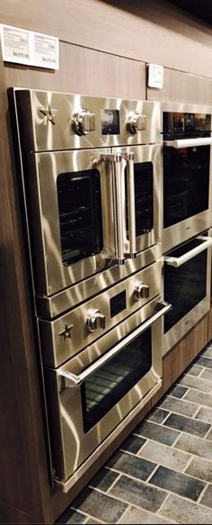 two ovens side by side on display in a kitchen with tile flooring and wooden cabinets