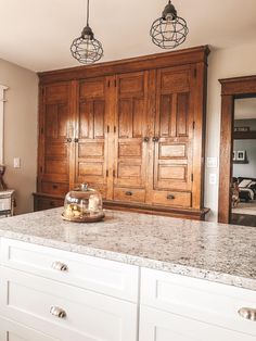 a kitchen with marble counter tops and wooden cabinets in the back wall, along with two hanging lights