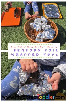 some kids are sitting on the grass and playing with tin foil wrapped to make toys