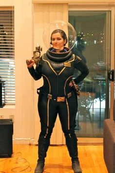 a woman dressed in black and gold holding a glass ball while standing on a hard wood floor