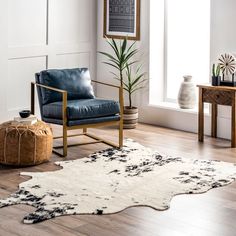 a living room with white walls and wooden flooring, a blue leather chair in front of a window