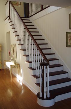 a white and brown stair case next to a wooden floor