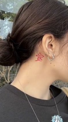 a woman with a red tattoo on her left side of her neck and behind her ear