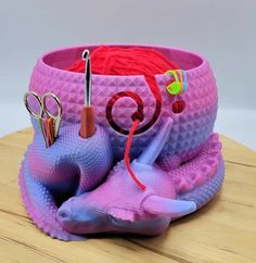 a pink and purple container with scissors, yarn and other items in it