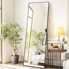 a large mirror sitting on top of a wooden floor next to a white couch and potted plant