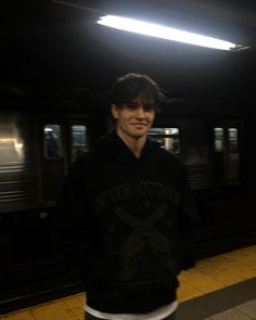 a young man standing in front of a subway train