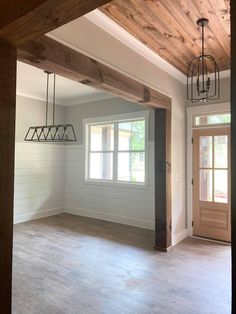 an empty living room with wood beams and light fixtures hanging from the ceiling above it