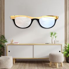 a pair of glasses hanging on the wall next to a white cabinet and stool with potted plants