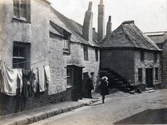 an old black and white photo of a person standing in front of some buildings with clothes hanging out to dry