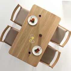 an overhead view of a wooden table with plates and bowls on it, along with two chairs