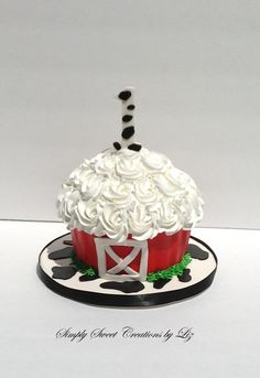 a red cupcake with white frosting and black polka dots on top, sitting on a plate