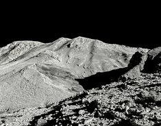 a black and white photo of mountains in the desert with no snow on them at night