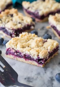 blueberry crumb bars are sitting on a table with a fork next to them