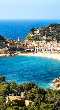 an aerial view of the beach and town from above, with blue water in the foreground