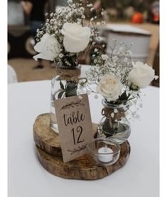 two vases filled with white flowers sitting on top of a table