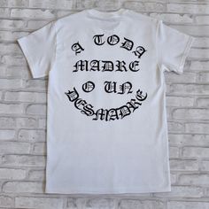 "\"A Toda Madre O Un Desmadre\", a motto we should all live by, we either win it all or lose everything. Font is in Spanish to represent our Hispanic Heritage. Screen printed design on the Back to remind the people walking behind you!" Inspirational Graphic Print Top For Streetwear, White Print Slogan Shirt For Streetwear, White Lettering T-shirt For Streetwear, Inspirational Cotton T-shirt For Streetwear, White T-shirt With Lettering For Streetwear, Band Merch T-shirt With Lettering For Streetwear, Lose Everything, People Walking, Hispanic Heritage