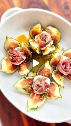 figs with prosciutto and herbs in a white bowl on a wooden table