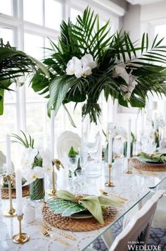 the table is set with white flowers and greenery