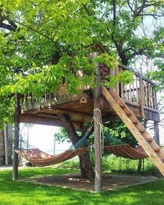 a tree house with a hammock in the yard