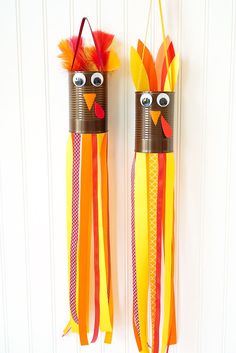 two tin can turkeys are hanging on the wall with their faces painted orange, yellow and red