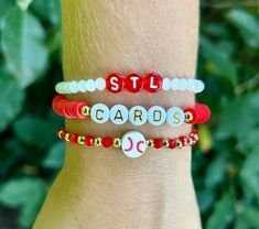 Let's Go Cards! This stack is perfect for any STL Cardinal baseball fan!  ⚾️It's made with gold beads, glass beads, letter beads, and a clay baseball bead, all strung together on strong stretch cord.  ⚾️All gold beads are 14K gold, non-tarnish beads.  ⚾️{Personalization}  These bracelets can be personalized. I can change the wording to anything. Ex: Player's name/number, birds, etc. Please let me know in the personalization box if you would like any words changed. Thank you!  ⚾️{Sizing} The average women's size is 7. I do make my bracelets in any size. To find your perfect fit, please see the item images for wrist measuring instructions.  Please feel free to reach out to me with any questions. Thank you! Adjustable Gold Beaded Bracelets For Game Day, Nfl Bracelets, Saint Louis Cardinals, Stl Cardinals Baseball, Team Bracelets, Baseball Bracelet, Football Bracelet, Jewels Diy, St Louis Cardinals Baseball