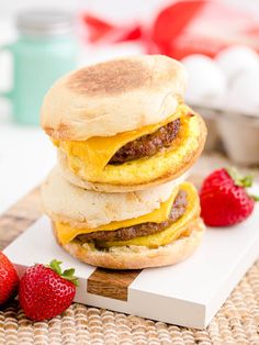 two breakfast sandwiches are stacked on top of each other with strawberries next to them