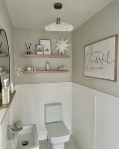 a white toilet sitting in a bathroom next to a sink and shelf with pictures on it