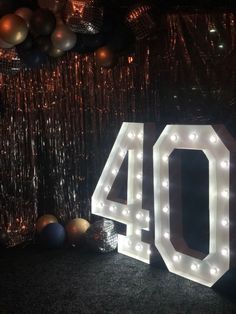 the number forty sits in front of balloons and streamers with lights on it's sides