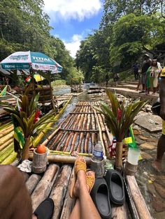 a person laying on top of a wooden raft next to trees and people standing around