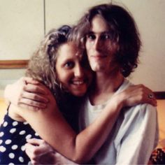 two people hugging each other in front of a bed