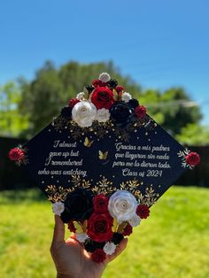 someone holding up a graduation cap with flowers on it