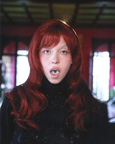 a woman with long red hair is making a funny face