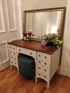 a dresser with a mirror and stool in front of it on a hard wood floor