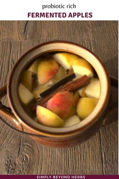 a cup filled with apples and cinnamon on top of a wooden table