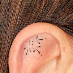 a close up of a person's ear with a small tattoo on it