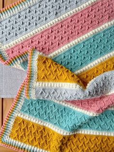 two crocheted afghans sitting next to each other on a wooden table top