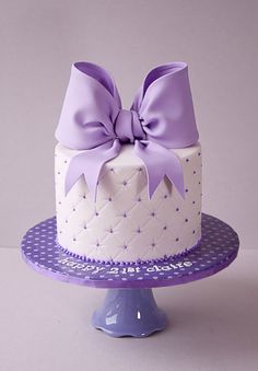 a white cake with purple bows on top is sitting on a blue plate and has an instagram post about it