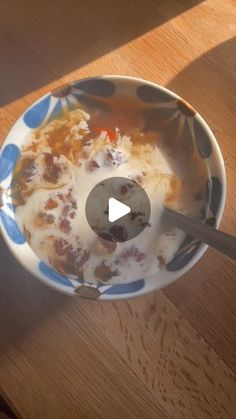 a bowl filled with food sitting on top of a wooden table next to a spoon