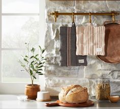 towels hanging on a rack next to a loaf of bread and a potted plant