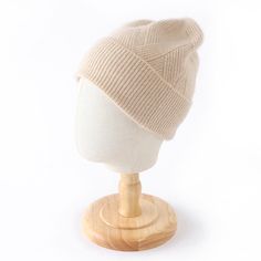 a white knitted hat sitting on top of a wooden stand