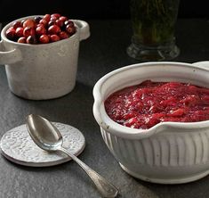 a bowl of cranberry sauce next to two bowls of berries